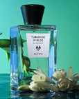 Beauty shot of ALTAIA Tuberose in Blue Eau de Parfum with top off and tuberose flowers in the background and foreground