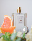 Lifestyle shot of ALTAIA Wonder of You Eau de Parfum (100 ml) with citrus slices and ingredients in the foreground