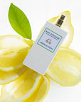 Lifestyle shot top view of Eau d'Italie Jardin du Poete Eau de Parfum Spray (100 ml) with lemons and single green leaf in the background