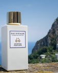 Lifestyle shot of Eau d'Italie Un Bateau Pour Capri Eau de Parfum Spray (100 ml) with Positano hillside in the background