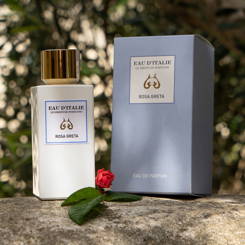 Lifestyle shot of Eau d'Italie Rosa Greta Eau de Parfum Spray bottle (100 ml) and box with a single pink rose bud in the foreground