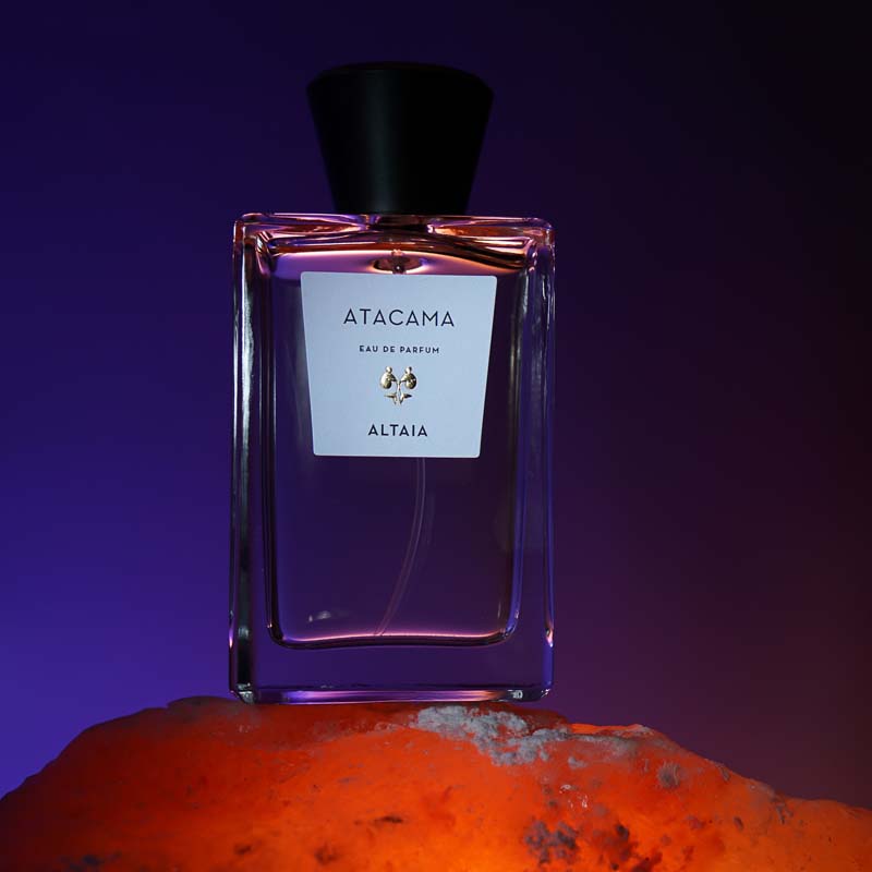 ALTAIA Atacama Eau de Parfum beauty shot with dark purple background and bottle on orange surface