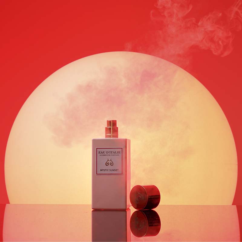 Eau d'Italie Mystic Sunset Eau de Parfum Spray showing with lid off in front of a sunset
