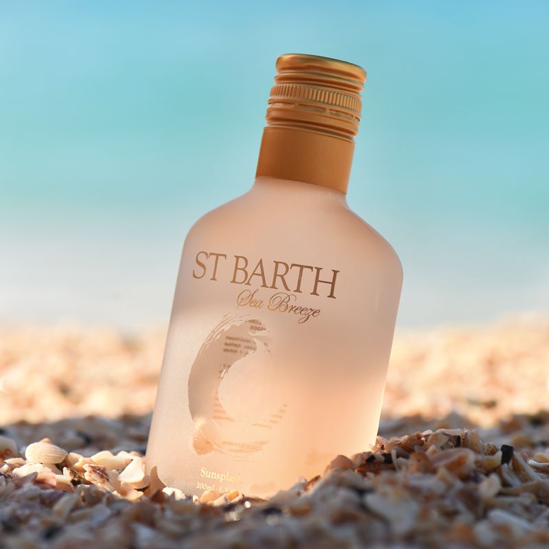 Beauty shot of Ligne St. Barth Sea Breeze Sunsplash Face &amp; Body Splash 200 ml on the beach with ocean in the background