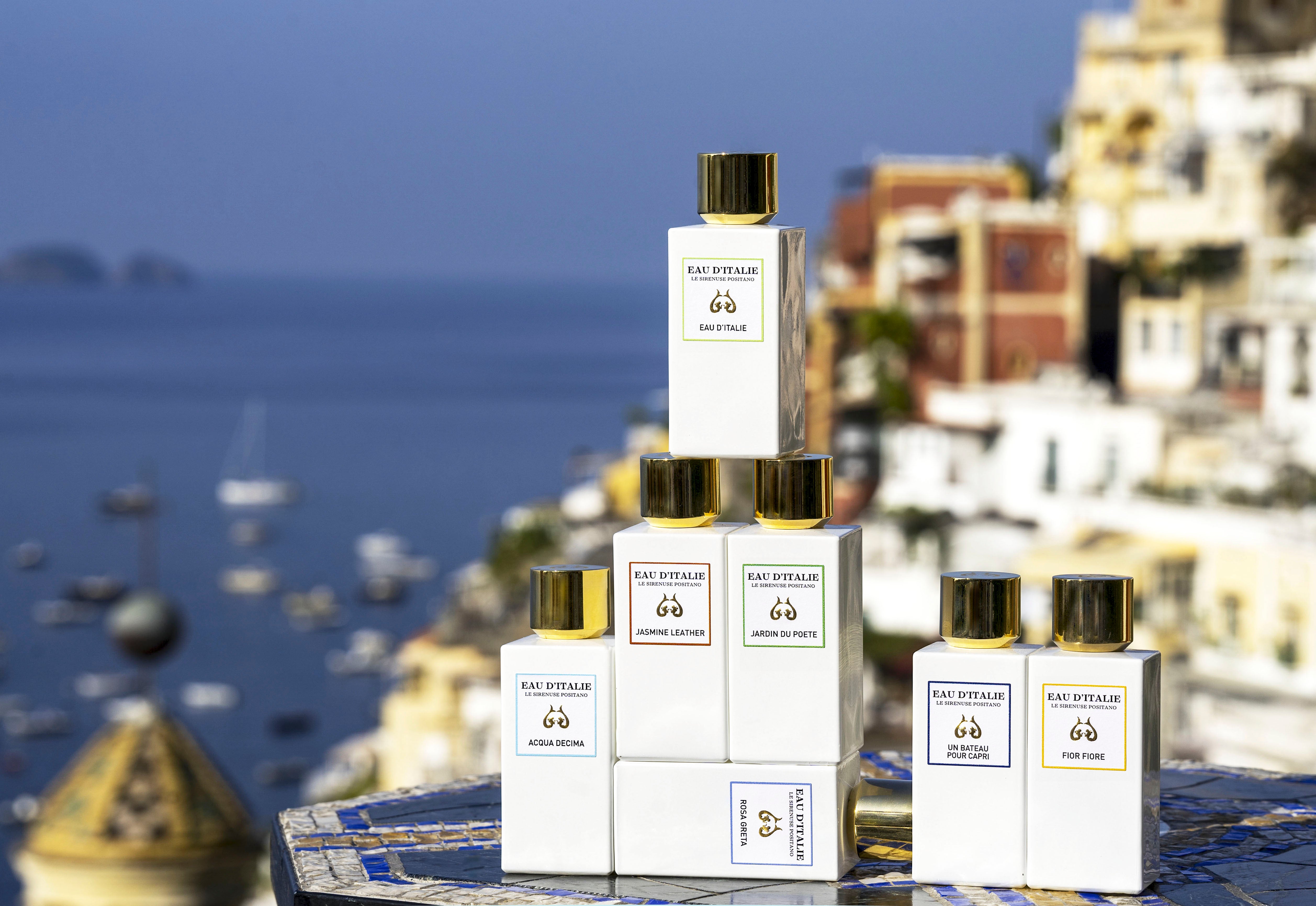 A selection of Eau d'Italie fragrances with the Positano hillside and ocean in the background