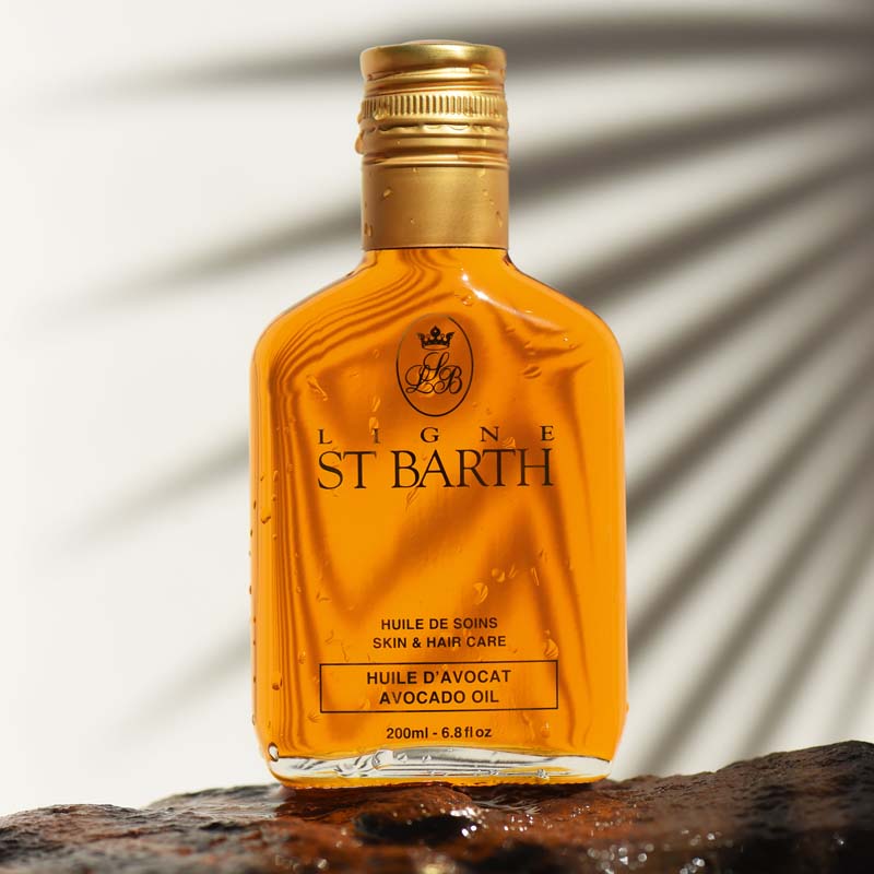 Ligne St. Barth Avocado Oil (6.8 oz) on stone with shadow of a palm leaf in the background