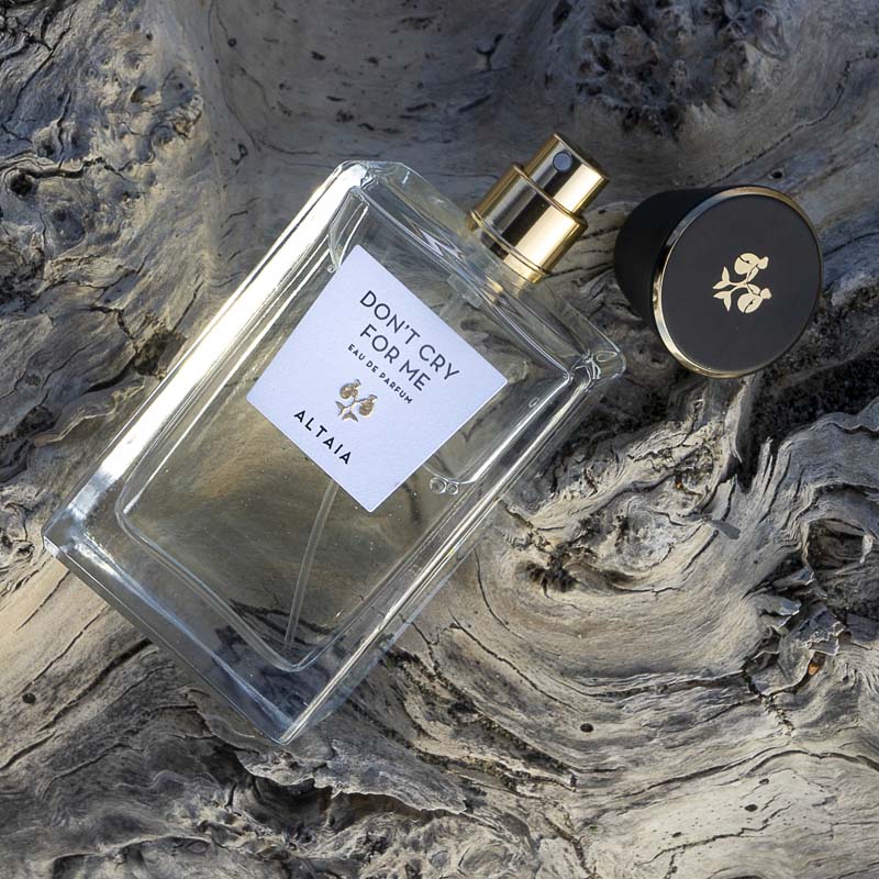 Beauty shot of ALTAIA Don&#39;t Cry For Me Eau de Parfum with cap off and wood in the background