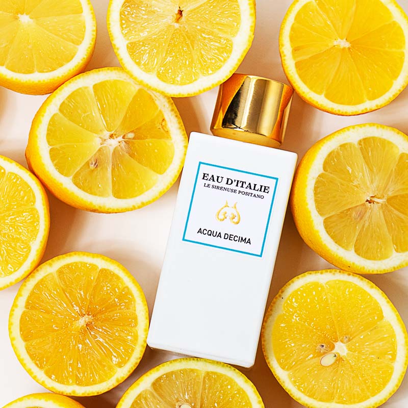 Lifestyle shot top view of Eau d'Italie Acqua Decima Eau de Parfum Spray (100 ml) with lemon slices around the bottle