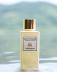 Lifestyle shot of Lifestyle shot top view of Eau d'Italie Acqua Decima Eau de Parfum Spray (100 ml) with lemon slices around the bottle sitting in water with mountainside in the background