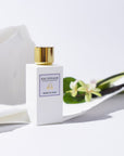 Lifestyle shot of Morn to Dusk Eau de Parfum Spray (100 ml) with white torn paper and white flowers in the background