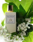 Lifestyle shot top view of Eau d'Italie Easy to Love Eau de Parfum Spray (100 ml) with white flowers and large green leaves in the background