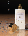 Lifestyle shot of Eau d'Italie Jasmine Leather Eau de Parfum Spray (100 ml) with cap off and water splash next to bottle
