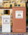 Lifestyle shot of Eau d'Italie Jasmine Leather Eau de Parfum Spray (100 ml) with box on tiled mosaic table and the Positano hillside in the background