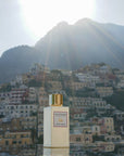 Eau d'Italie Mystic Sunset Eau de Parfum Spray (100 ml) with the Positano cliffside in the background