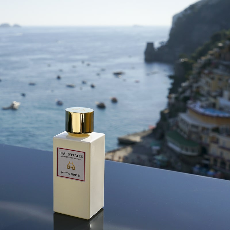 Eau d&#39;Italie Mystic Sunset Eau de Parfum Spray (100 ml) with the Positano cliffside and bay in the background